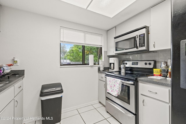 kitchen featuring tasteful backsplash, white cabinetry, appliances with stainless steel finishes, and light tile patterned floors