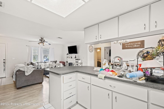 kitchen featuring white cabinets, light wood-type flooring, kitchen peninsula, and ceiling fan