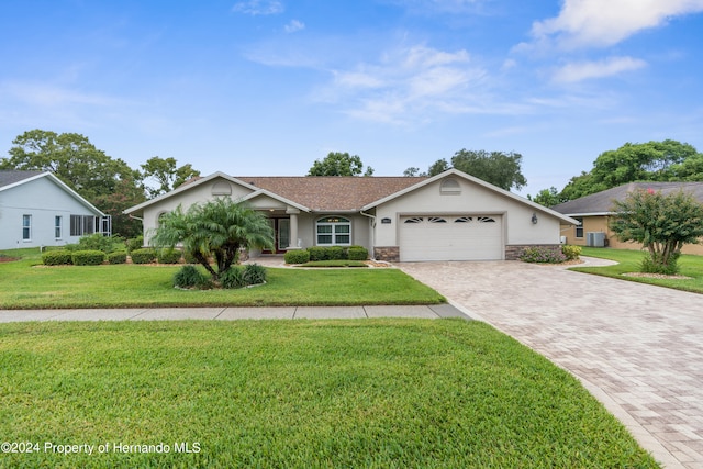 ranch-style home featuring central air condition unit, a garage, and a front yard