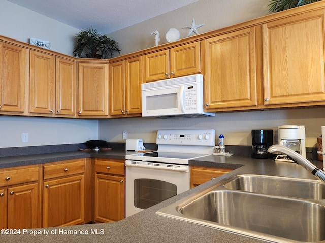 kitchen with white appliances, sink, and a textured ceiling