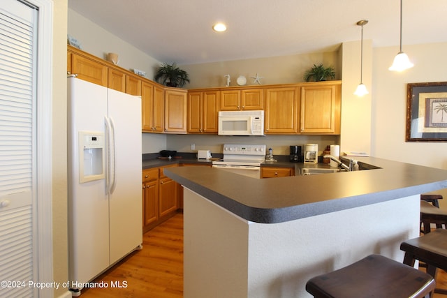 kitchen with kitchen peninsula, dark hardwood / wood-style flooring, pendant lighting, sink, and white appliances