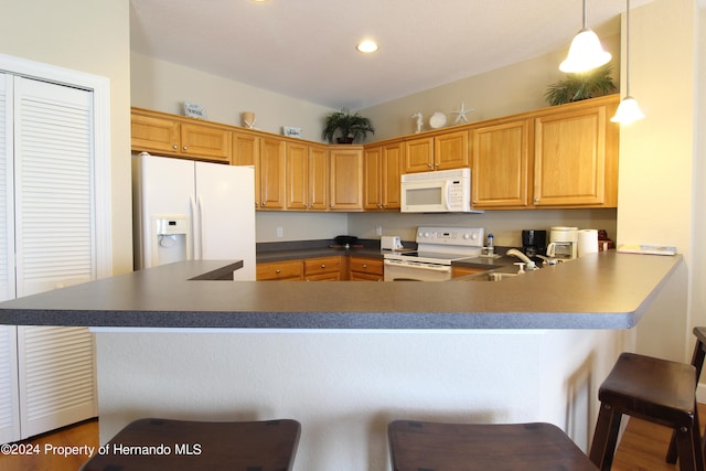 kitchen with kitchen peninsula, sink, a breakfast bar, pendant lighting, and white appliances