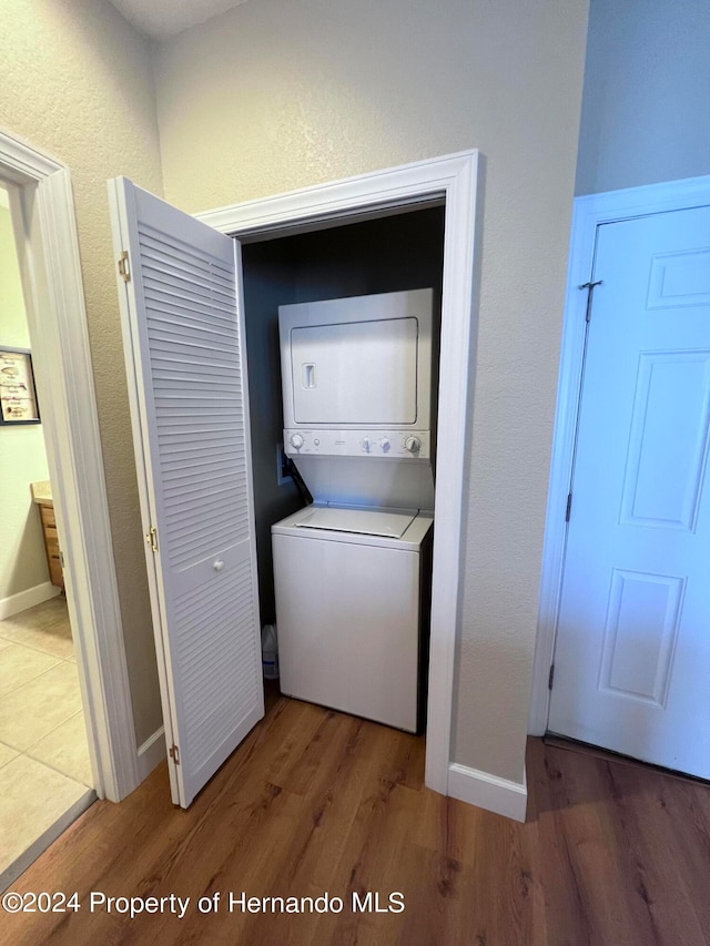 washroom featuring wood-type flooring and stacked washer / drying machine