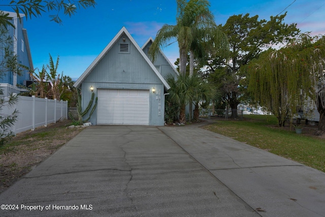 property exterior at dusk featuring a garage and a yard