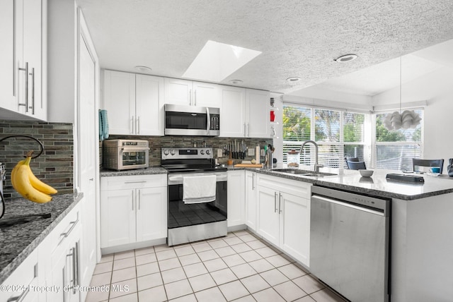 kitchen with stainless steel appliances, white cabinetry, sink, a textured ceiling, and backsplash