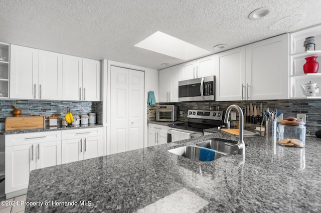 kitchen featuring dark stone countertops, backsplash, white cabinets, and stainless steel appliances