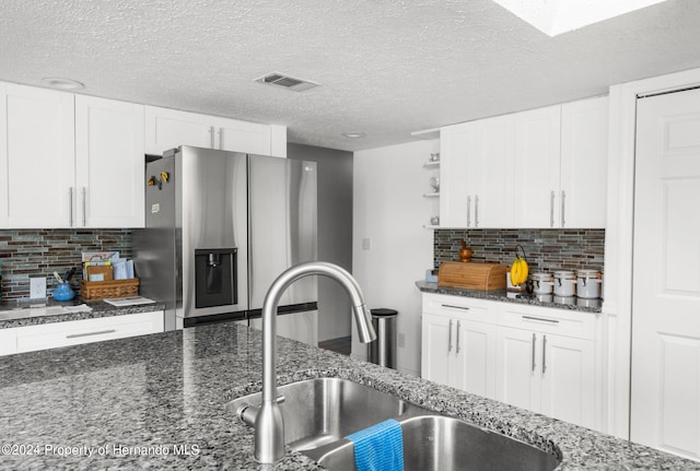 kitchen with white cabinets, stainless steel fridge with ice dispenser, sink, and decorative backsplash