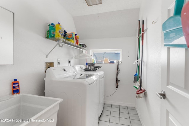 clothes washing area featuring a textured ceiling, washing machine and dryer, light tile patterned floors, and sink