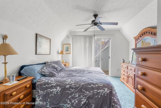 carpeted bedroom with a textured ceiling, multiple windows, ceiling fan, and vaulted ceiling