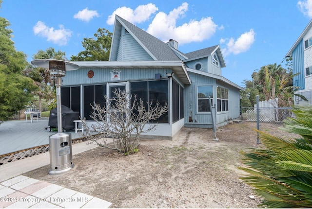 back of property with a deck and a sunroom