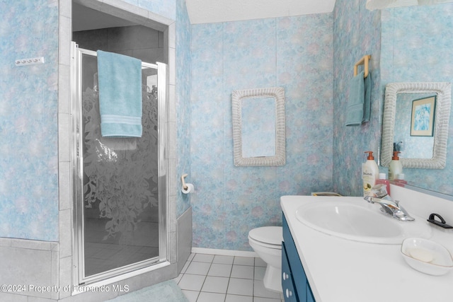 bathroom featuring toilet, vanity, tile patterned flooring, and a shower with shower door