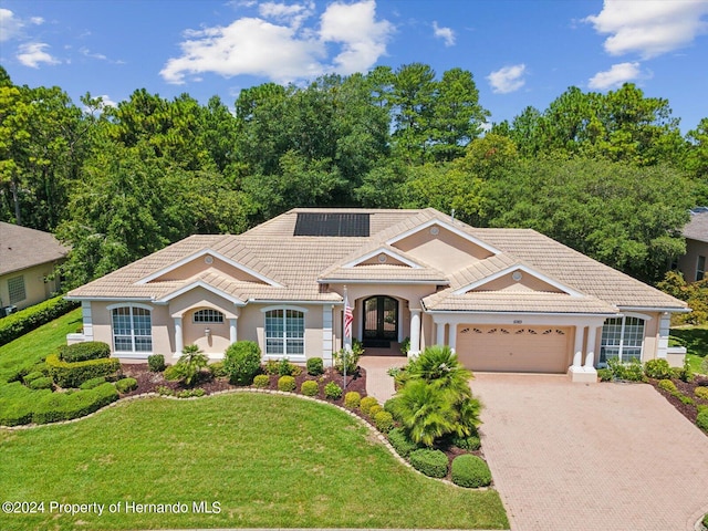 view of front of property with a front lawn, a garage, and solar panels