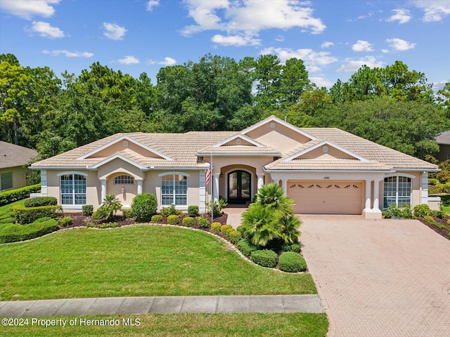 view of front facade with a front yard, french doors, and a garage