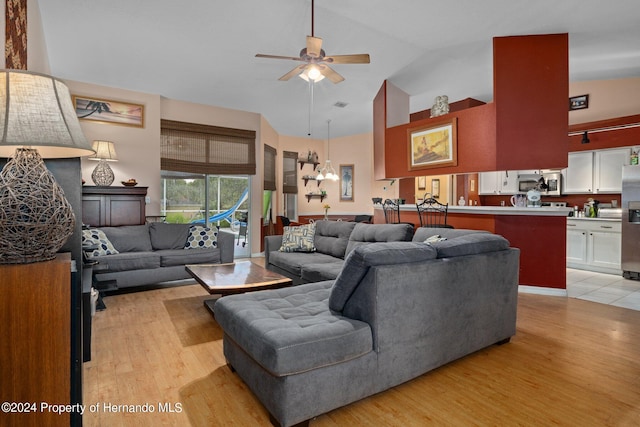 living room with light hardwood / wood-style floors, ceiling fan with notable chandelier, and high vaulted ceiling