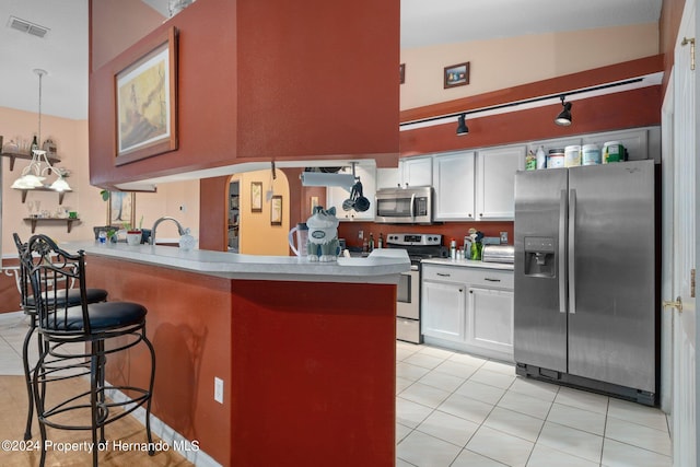 kitchen featuring appliances with stainless steel finishes, pendant lighting, a breakfast bar, white cabinets, and lofted ceiling