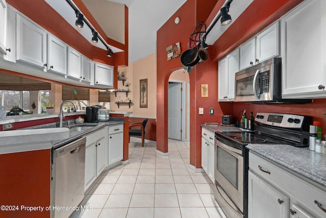 kitchen featuring stainless steel appliances, light tile patterned flooring, white cabinets, and sink