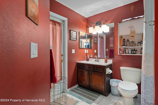 bathroom with toilet, vanity, and tile patterned floors