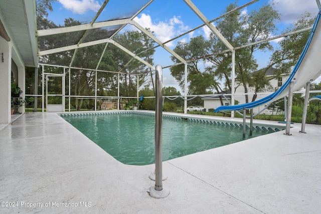 view of pool featuring glass enclosure, a patio, and a water slide