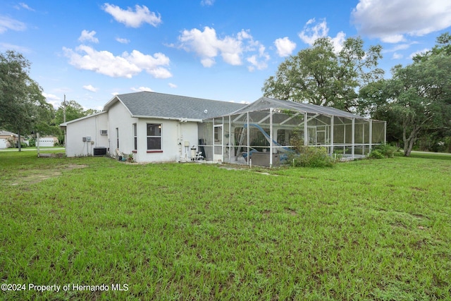 rear view of property with a yard, a lanai, and cooling unit