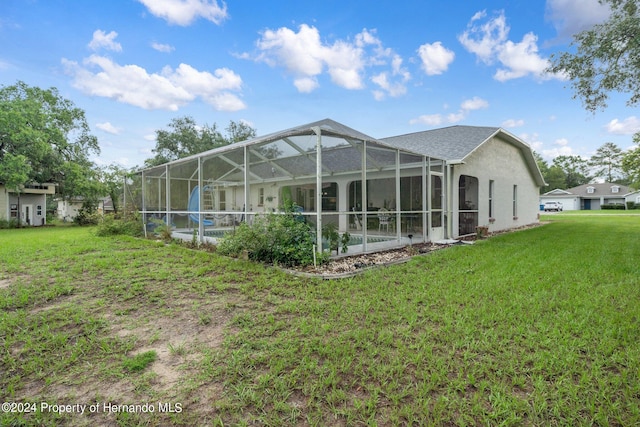 rear view of house featuring glass enclosure and a yard