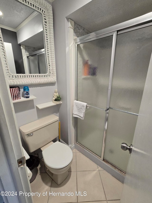 bathroom with toilet, a textured ceiling, tile patterned floors, and a shower with shower door