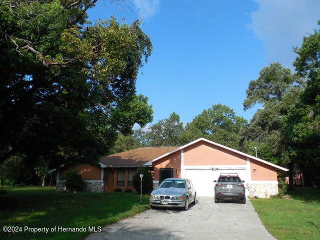 ranch-style home with a garage and a front lawn