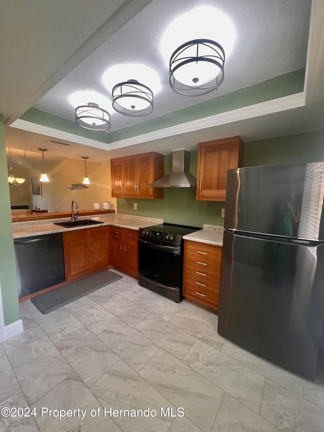 kitchen with a raised ceiling, black appliances, sink, and wall chimney range hood