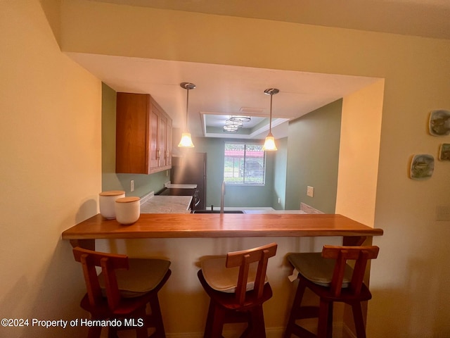 kitchen with sink, kitchen peninsula, ornamental molding, a breakfast bar area, and pendant lighting