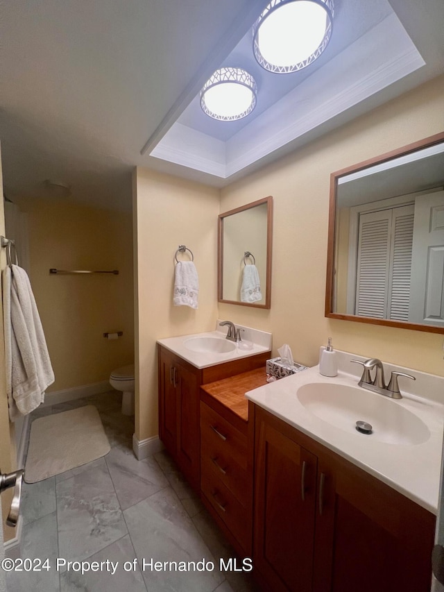 bathroom with toilet, vanity, and a raised ceiling