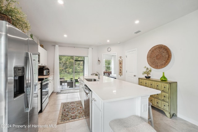 kitchen with green cabinets, white cabinetry, appliances with stainless steel finishes, a breakfast bar area, and an island with sink