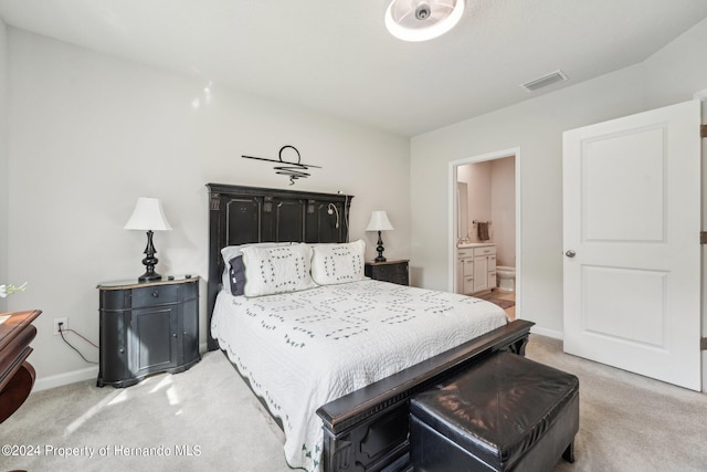 bedroom with connected bathroom and light colored carpet