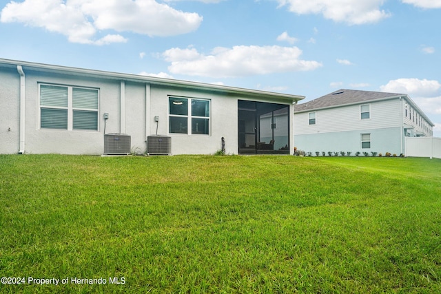 rear view of property featuring a lawn, a sunroom, and central AC