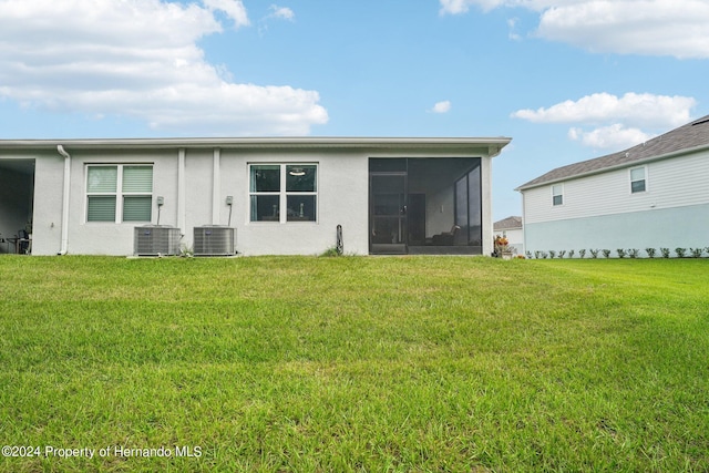 back of house featuring central AC unit, a lawn, and a sunroom