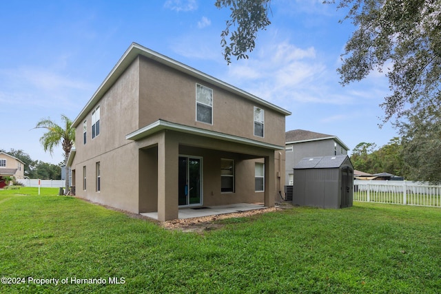 rear view of house featuring a patio area, a yard, and a storage shed