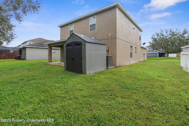 back of property featuring a storage shed, a yard, and central AC