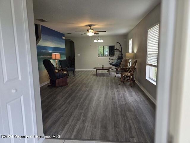 living area with ceiling fan, a healthy amount of sunlight, and dark wood-type flooring