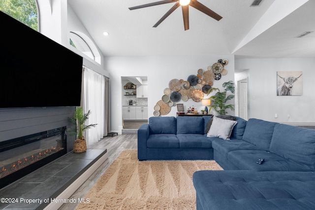 living room featuring ceiling fan, a healthy amount of sunlight, light hardwood / wood-style flooring, and vaulted ceiling