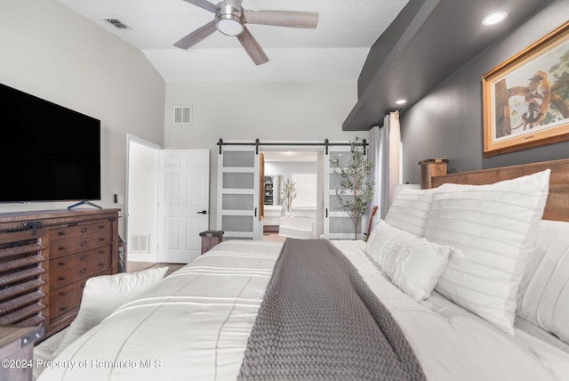 bedroom featuring hardwood / wood-style floors, a barn door, vaulted ceiling, and ceiling fan