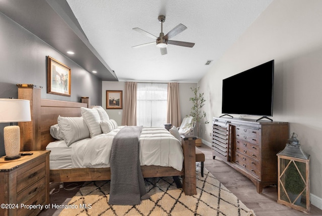 bedroom featuring a textured ceiling, light wood-type flooring, ceiling fan, and vaulted ceiling