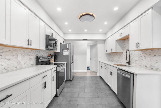 kitchen with white cabinets, decorative backsplash, appliances with stainless steel finishes, and sink