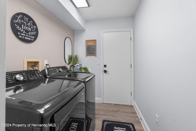 laundry room with hardwood / wood-style flooring and washing machine and clothes dryer