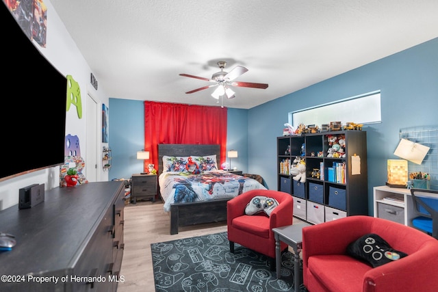 bedroom with ceiling fan, wood-type flooring, and a textured ceiling