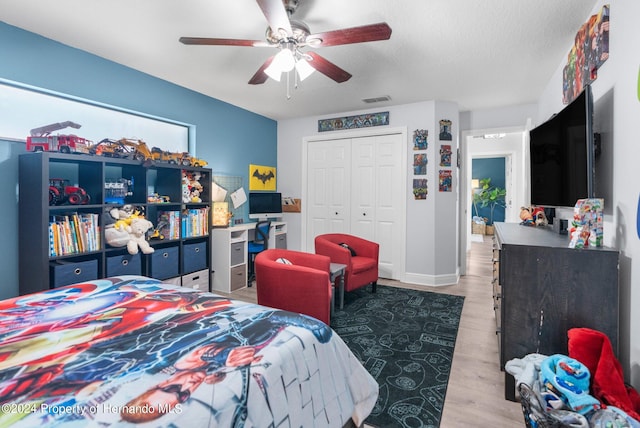 bedroom featuring a textured ceiling, wood-type flooring, ceiling fan, and a closet