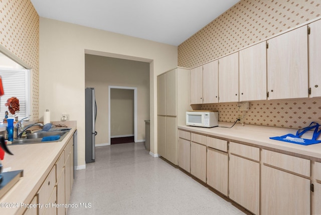 kitchen with light brown cabinets, sink, and stainless steel fridge