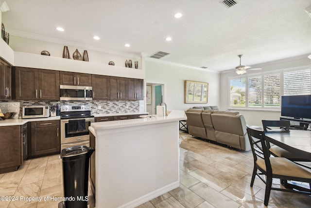 kitchen featuring stainless steel appliances, ceiling fan, decorative backsplash, and ornamental molding