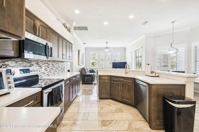 kitchen with sink, tasteful backsplash, crown molding, pendant lighting, and appliances with stainless steel finishes