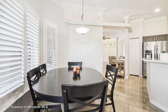 dining space featuring crown molding and decorative columns