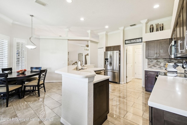 kitchen with stainless steel appliances, decorative light fixtures, backsplash, dark brown cabinets, and a kitchen island with sink