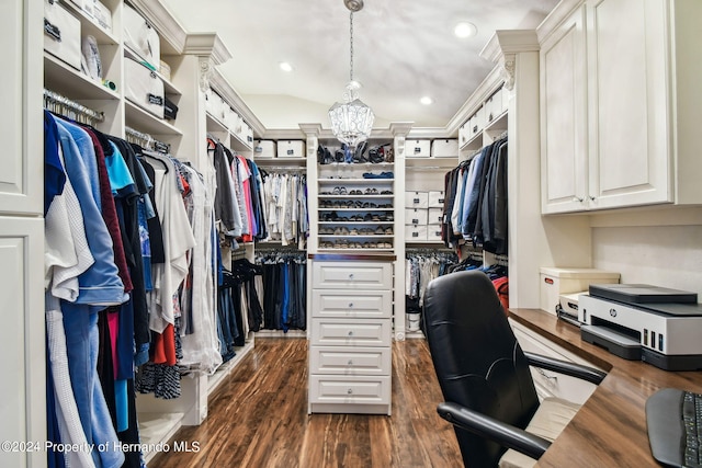 walk in closet with dark wood-type flooring, lofted ceiling, and a notable chandelier