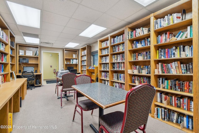 office space with a paneled ceiling and light carpet